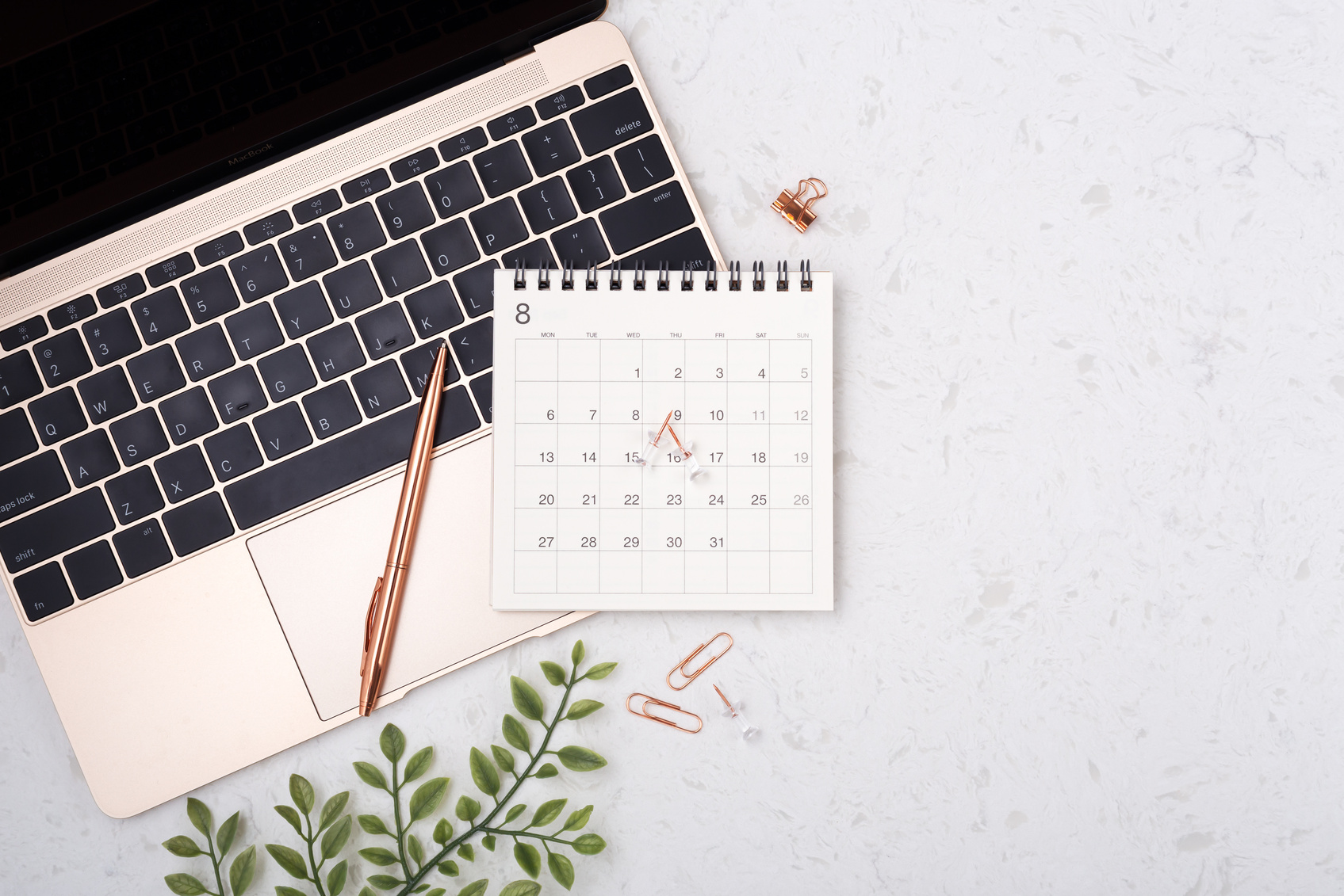 Calendar with rose gold pen on laptop